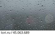 Heavy raindrops tapping on the window pane. Raindrops flowing down the window pane during a downpour. Rainy weather. Капли дождя стучат по стеклу во время ливня. Стоковое видео, видеограф Ольга Петрова-Апостолова / Фотобанк Лори