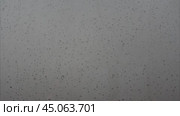 Heavy raindrops tapping on the window pane. Raindrops flowing down the window pane during a downpour. Rainy weather. Капли дождя стучат по стеклу во время ливня. Стоковое видео, видеограф Ольга Петрова-Апостолова / Фотобанк Лори