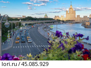Вид на автомобильное движение на Москворецкой набережной Москвы-реки, парящий мост и высотное здание на Котельнической набережной (2024 год). Редакционное фото, фотограф Pukhov K / Фотобанк Лори