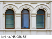 Front view on a facade of ancient stone building with three arched windows with carved platbands. Стоковое фото, фотограф Михаил Строгалев / Фотобанк Лори