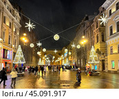 SAINT PETERSBURG, RUSSIA-December 25, 2023: People walking on Bolshaya Morskaya Street decorated with garlands and Christmas trees near arch of General Staff Building in New Year and Christmas holidays. Редакционное фото, фотограф Виктория Катьянова / Фотобанк Лори
