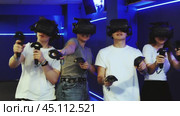 Group of excited young people with handheld controllers in hands engaged in virtual world experiencing through VR glasses covering face. Concept of immersion and interactivity in game. Стоковое видео, видеограф Яков Филимонов / Фотобанк Лори