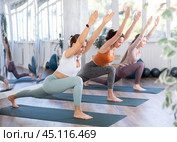 Young woman standing in Ashta Chandrasana balancing asana at yoga training. Стоковое фото, фотограф Яков Филимонов / Фотобанк Лори