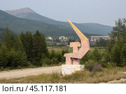 Стела «Серп и молот» на въезде в посёлок Атка, Магаданская область, Россия. Скульптурная композиция с изображением символов Советского Союза - серпа и молота. Вдали заброшенные дома в покинутом северном посёлке. После развала Советского Союза из Атки произошёл большой отток населения. С 2020 года по решению областной администрации проходило переселение жителей Атки в посёлок Палатка и город Магадан, завершившееся в 2023 году. Редакционное фото, фотограф Андрей Степанов / Фотобанк Лори