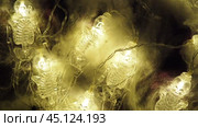 Transparent skeletons glowing yellow, close-up. Transform your space with a whimsical garland featuring glowing skeleton skulls and bones, perfect for Halloween festivities and ambiance. Horror theme. Стоковое видео, видеограф Юлия Петровская / Фотобанк Лори