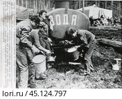 Мужчины набирают и пьют воду из водовозки. БАМ, 1974 г, посёлок "Звездный" – первая станция западного участка Байкало-Амурской магистрали. Стоковое фото, фотограф Retro / Фотобанк Лори
