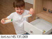 A child boy is holding a lit matchstick, which is highly flammable and risky. The baby is dangerously playing with a flame inside the house. Kid aged 3 years (three year old boy) Стоковое фото, фотограф Андрей Журавлев / Фотобанк Лори