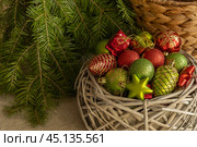 Елочные украшения - красные и зеленые шары, шишки, звезды в корзине под елкой. Стоковое фото, фотограф Оксана Шведкова / Фотобанк Лори