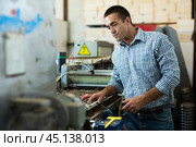 Farmer man working with automatic filling and seeding line for growing containerized seedlings of decorative plants in greenhouse. Стоковое фото, фотограф Яков Филимонов / Фотобанк Лори