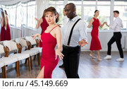 Woman dances incendiary boogie woogie with African man partner during choreography lesson. Стоковое фото, фотограф Яков Филимонов / Фотобанк Лори