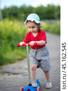 Little girl on scooter with scraped knees on walk. Стоковое фото, фотограф Анна Никонорова / Фотобанк Лори