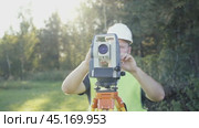 Male engineer surveyor near a surveying instrument preparing to start taking precise measurements. Geodetic work, topography, land surveying, cadastral work. Стоковое видео, видеограф Скрипачев Антон / Фотобанк Лори