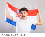 Happy young man holding flag of Croatia against unicoloured background. Стоковое фото, фотограф Яков Филимонов / Фотобанк Лори