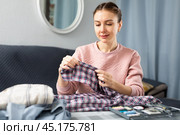Woman sewing button on shirt sleeve at home. Стоковое фото, фотограф Яков Филимонов / Фотобанк Лори