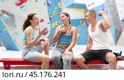 Three friends, man and woman, discuss their climbs on climbing wall without safety net, sitting on bench in a recreation area. Стоковое видео, видеограф Яков Филимонов / Фотобанк Лори