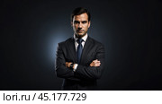 Successful businessman with crossed arms in magnificent suit stands on dark background. portrait of charismatic billionaire. Стоковое AI-изображение, AI-художник Павел Муравьев / Фотобанк Лори