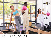 African american trainer teaches women to do pilates with pink balls. Стоковое фото, фотограф Яков Филимонов / Фотобанк Лори