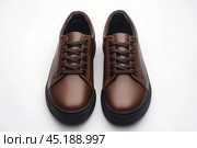Dark brown leather lace-up running shoes with low tops, thick soles. The laces and black rubber outsole. Sporty look. Men to wear during outdoor activities, hiking. Brown shoes. Trendy Male Boots Pair. Стоковое AI-изображение, AI-художник Марина Демидюк / Фотобанк Лори