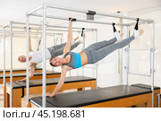 Young woman performing side hanging exercise on Pilates trapeze table. Стоковое фото, фотограф Яков Филимонов / Фотобанк Лори