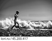Мальчик бежит по берегу моря на фоне волн.Чб. Редакционное фото, фотограф Оксана / Фотобанк Лори