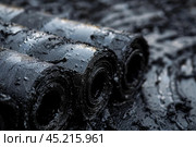 Rolls of black roofing felt covered with bitumen getting ready to be installed on a roof. Стоковое AI-изображение, AI-художник Иван Рябоконь / Фотобанк Лори