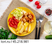 baked potato slices and turkey stew with vegetables on bright yellow plate, on white rustic background, top view, overhead. Стоковое фото, фотограф Natalia Gdovskaia / Фотобанк Лори