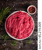 Mince beef, ground meat with ingredients for cooking on dark blue. Стоковое фото, фотограф Natalia Gdovskaia / Фотобанк Лори