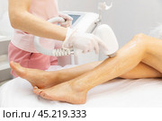 Diode laser epilation hair removal procedure on a woman leg. Beautician doing laser rejuvenation in a beauty salon. Removing unwanted body hair. Hardware cosmetology. High quality photo. Стоковое фото, фотограф Ирина Михайличенко / Фотобанк Лори