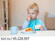 Unhealthy food for children. Eating. A cute 2-year-old kid eats pizza for lunch. Fast food. Family and children. Стоковое фото, фотограф Photojuli / Фотобанк Лори