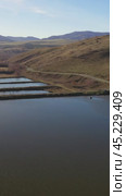 Vertical drone video of flying over a hilly rural landscape with a winding road and fish ponds. Altai Krai. Стоковое видео, видеограф Сергей Пристяжнюк (Serg Zastavkin) / Фотобанк Лори