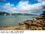 Nha Trang Vietnamese resort coastline is revealed in vibrant spectacle. picturesque rocky coast meet azure sea under radiant sun, panorama of beaches and crystal-clear waters. Стоковое фото, фотограф Павел Муравьев / Фотобанк Лори