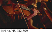 The violinist performs in warm, diffused lighting. Close-up of the violin body, movements of the bow on the strings and the musician's hand. Passion and mastery of classical music. Стоковое видео, видеограф Воловодов Владимир / Фотобанк Лори