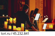A group of musicians performing on stage or in a concert hall. The ensemble consists of string instruments, double bass, cello and violins. Stage is decorated with candles. Russia, September 2, 2024. Редакционное видео, видеограф Воловодов Владимир / Фотобанк Лори