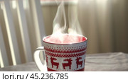 Steaming Cup of Coffee or Tea on Table. White linen Tablecloth. Close up ceramic red Christmas mug with smoke on old table in dining room interior background. Hot Drink Concept. Cozy Morning. Стоковое видео, видеограф Марина Демидюк / Фотобанк Лори