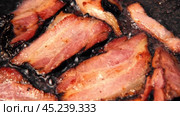 Frying Bacon Slices in a Pan. Crispy Pieces of Delicious Red Thin Smokey Bacon Fried in a Hot Skillet. Traditional Breakfast. Smoked Bacon Rasher or Strip Being Cooked. Grill. Fat High Calorie Food. Стоковое видео, видеограф Марина Демидюк / Фотобанк Лори