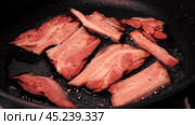 Frying Bacon Slices in a Pan. Crispy Pieces of Delicious Red Thin Smokey Bacon Fried in a Hot Skillet. Traditional Breakfast. Smoked Bacon Rasher or Strip Being Cooked. Grill. Fat High Calorie Food. Стоковое видео, видеограф Марина Демидюк / Фотобанк Лори