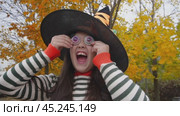 Playful witch costume and candy eyes in autumn forest setting. Стоковое видео, видеограф Zakharova Natasha / Фотобанк Лори