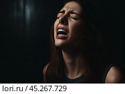 Beautiful face of sad woman screaming crying desperate and depressed with tears on her eyes suffering pain and depression isolated on black background in sadness facial expression and emotion concept. Стоковое AI-изображение, AI-художник Sergey Grishin / Фотобанк Лори