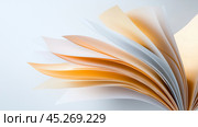 Open book with colorful pages fanned out against a light background highlighting the texture and layers of paper. Стоковое AI-изображение, AI-художник Сергей Толмачёв / Фотобанк Лори