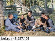 Positive paintball players sitting on battleground and chatting. Стоковое фото, фотограф Яков Филимонов / Фотобанк Лори