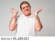 Middle-aged man gestures with a shrug and a smile, conveying a sense of confusion or indifference. Стоковое фото, фотограф Сергей Толмачёв / Фотобанк Лори