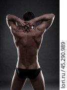 Handsome muscular bodybuilder posing on gray background. Low key studio shot. Стоковое фото, фотограф Станислав Тарко / Фотобанк Лори