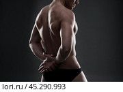 Handsome muscular bodybuilder posing on gray background. Low key studio shot. Стоковое фото, фотограф Станислав Тарко / Фотобанк Лори