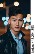 A young man with a confident expression poses against a backdrop of colorful lights at night in urban setting. A resident of Kazakhstan, a cute man of 25 years old. Student or applicant. AI generated. Стоковое AI-изображение, AI-художник Юлия Петровская / Фотобанк Лори
