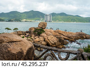 Nha Trang's scenic coastline with rocky shore, and modern high-rise hotels. rugged beauty of stone-strewn coast meets sandy haven, framed by contemporary architecture under Vietnamese sun. Стоковое фото, фотограф Павел Муравьев / Фотобанк Лори