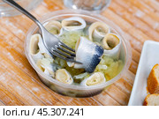 Invisible hand holds fork with pierced piece of salted herring fillet. Стоковое фото, фотограф Яков Филимонов / Фотобанк Лори