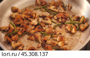 There is frying pan with pieces of champignons and green asparagus shoots on gas stove. Home cooking of delicious dishes according to recipes of cookbook. Стоковое видео, видеограф Яков Филимонов / Фотобанк Лори