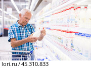 Old age man choosing milk in supermarket. Стоковое фото, фотограф Татьяна Яцевич / Фотобанк Лори