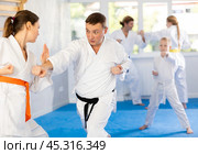 Woman is paired with man teacher to learn how to strike and rehearses blocking opponent. Стоковое фото, фотограф Яков Филимонов / Фотобанк Лори