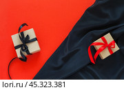 Black Friday. Sale of goods at reduced prices concept. Two gift boxes made of eco kraft paper, one with black bow on red background, second with red bow on  black silk background. Flat lay, copy space. Стоковое фото, фотограф Виктория Катьянова / Фотобанк Лори